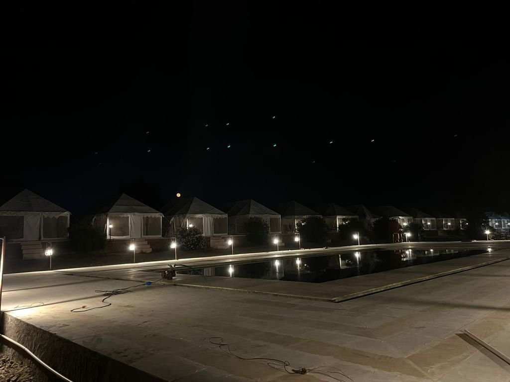 Wide view of pool and tents at night