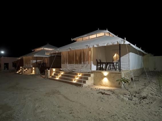 Tents illuminated at night with dining setup