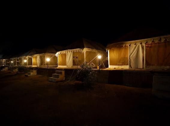 Row of luxury tents lit up at night at Royal Sun Desert Camp